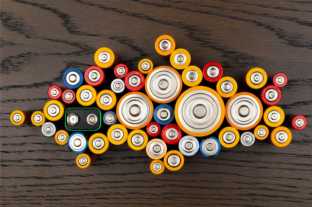 Mixed batteries of different sizes and colours arranged on a dark surface