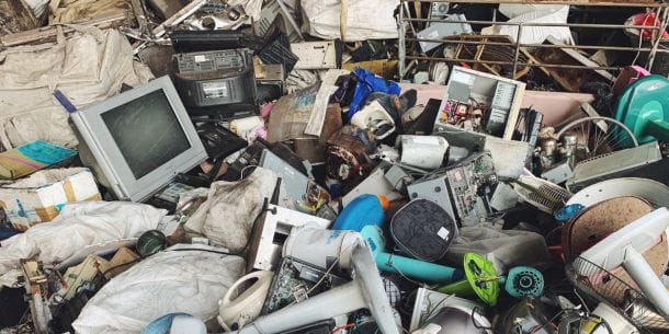 Pile of discarded electronic appliances including monitors, fans, and radios