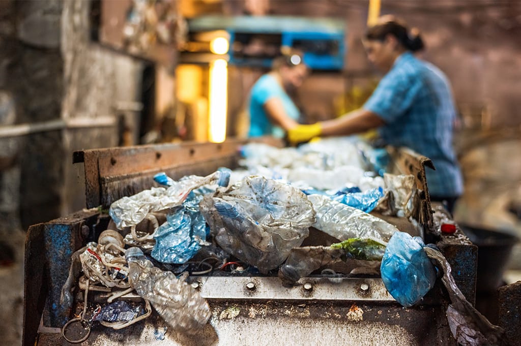 Plastic waste being sorted on a conveyor belt at a recycling facility