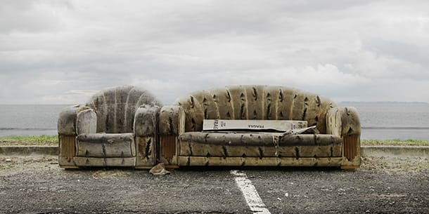 Old, damaged upholstered sofa and chair left outdoors