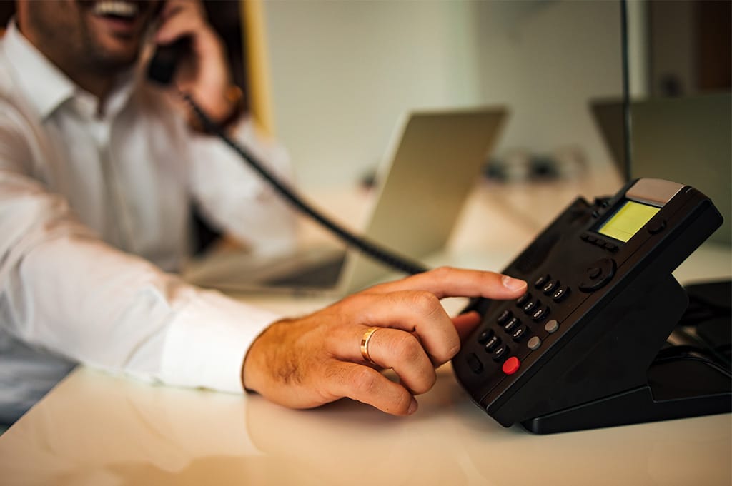 Person making a business phone call while sitting at a desk with a landline