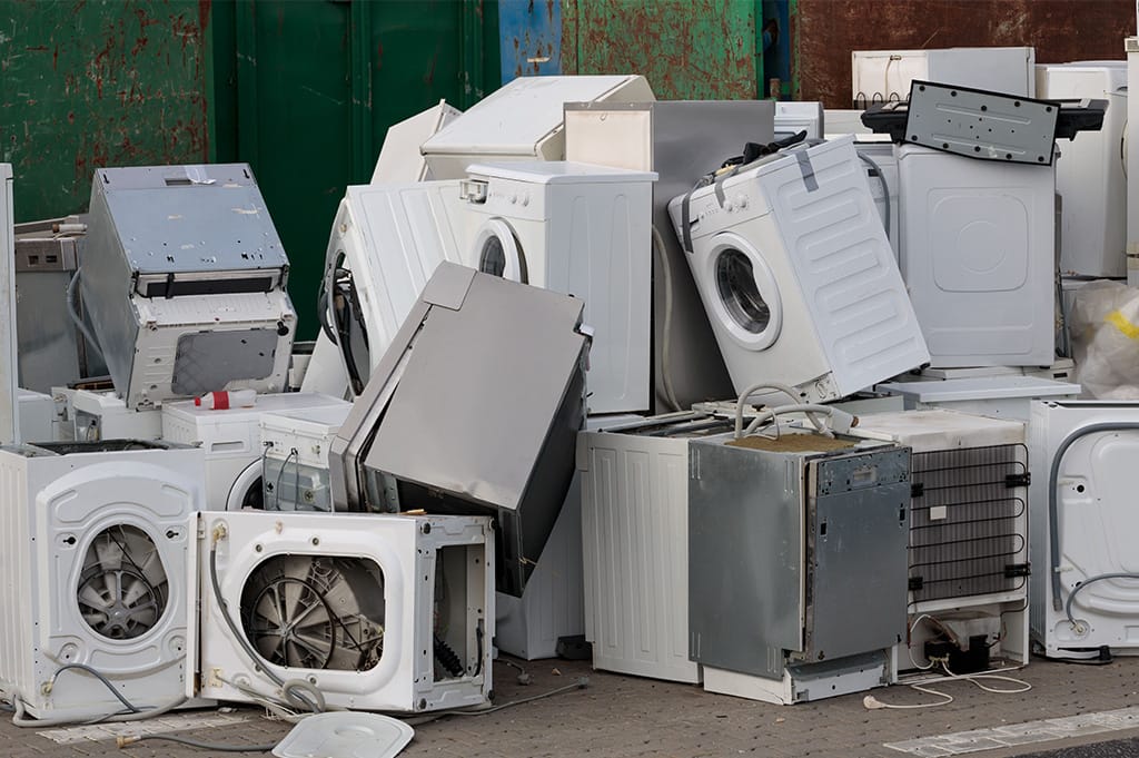 Pile of broken white goods including washing machines and appliances